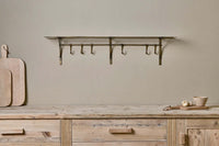 Basti antique brass shelf mounted above a wooden sideboard