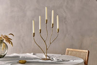 Palani antique brass branching candelabra shown against a neutral wall