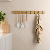 Umbra Flip 8 hook rail mounted in a kitchen holding utensils and a tea towel