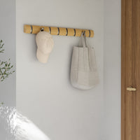 Umbra Flip 8 hook rail mounted on a wall holding a cap and tote bag