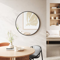 Umbra Hub black round mirror mounted above a green sofa in a living room