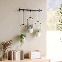 Umbra Triflora hanging planters mounted on a wall against a neutral backdrop